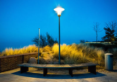 Illuminated street light against clear blue sky