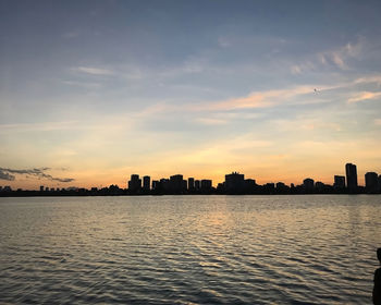 Silhouette buildings by city against sky during sunset