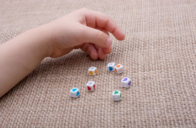 Cropped hand of child playing with beads on burlap