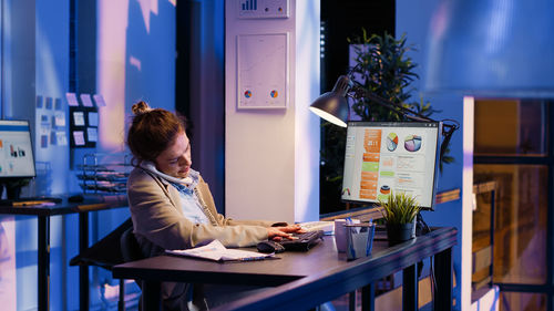 Side view of woman using laptop at table