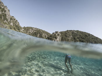 Low section of woman standing in sea