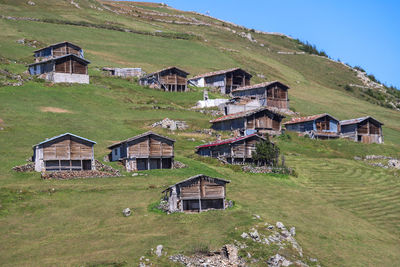 Houses on field by buildings against sky