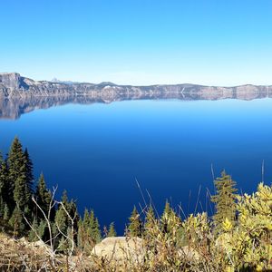 Scenic view of lake and mountains against clear blue sky