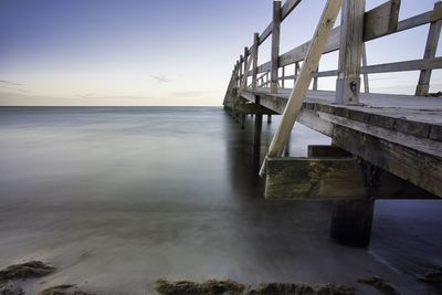 Pier over sea against sky during sunset