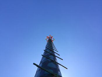 Low angle view of flags against building against clear blue sky