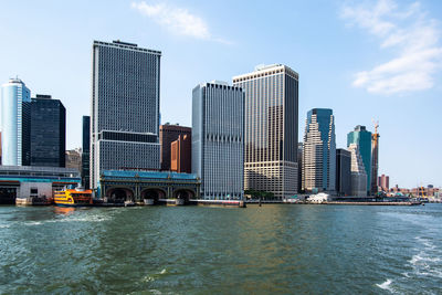 Modern buildings by river against sky in city