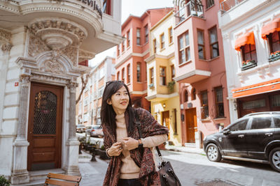 Young woman standing against building