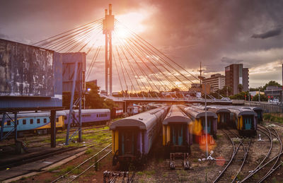 Trains at shunting yard against sky during sunset