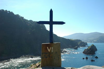 Cross on sea against clear sky