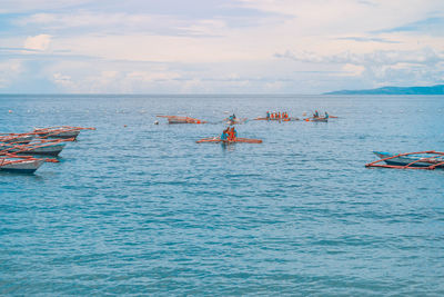 People boating on sea against sky