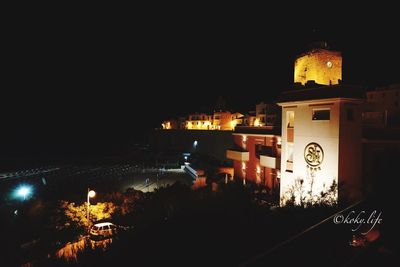 High angle view of illuminated street amidst buildings in city at night