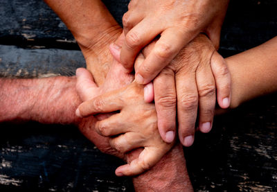 Close-up of people stacking hands on wood