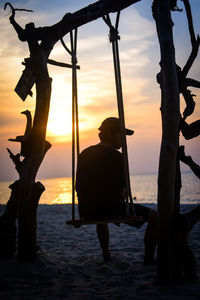 Silhouette man standing on beach against sky during sunset