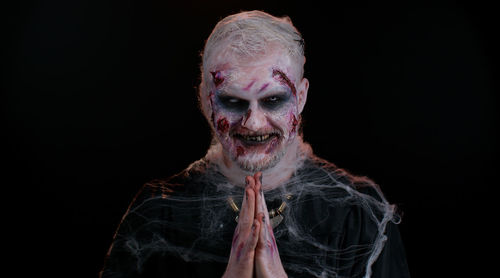 Portrait of zombie against black background