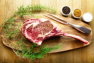 Raw waguy tomahawk steak on wooden background with spices ready forthe bbq