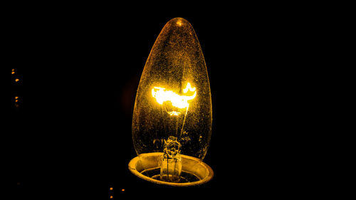 Close-up of illuminated light bulb against black background