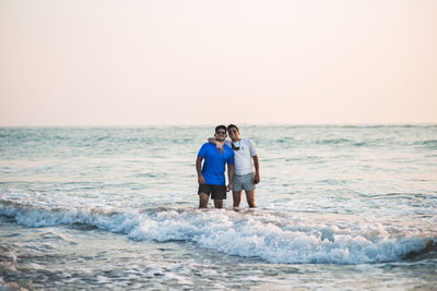 Rear view of man standing at beach against clear sky