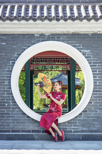 Portrait of smiling young woman standing against building