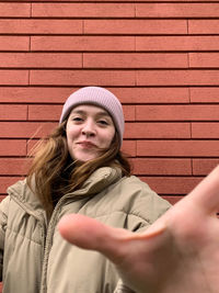 Portrait of young woman against wall