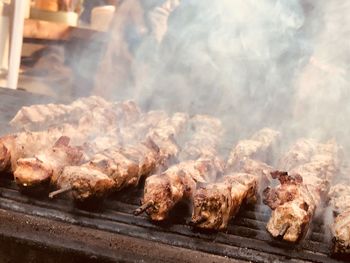 Midsection of man standing by preparing meat on barbecue grill