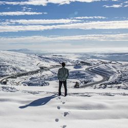 Rear view of man standing on snowcapped mountain