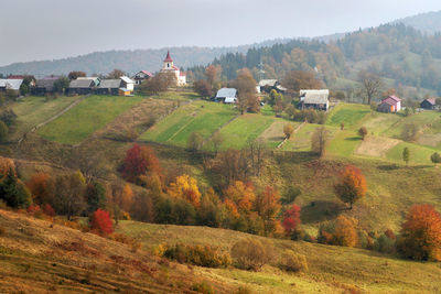 Scenic view of trees and houses on field