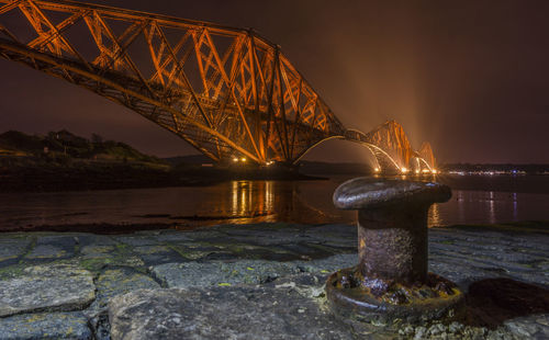 Illuminated suspension bridge over river at night