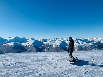 Full length of person on snowcapped mountain against clear blue sky