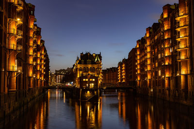 Illuminated wasserschloss in speicherstadt hamburg in docklands at night reflecting in the water