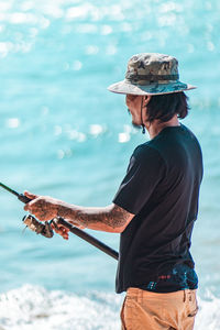 Low section of man standing by sea