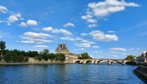 Arch bridge over river against cloudy sky