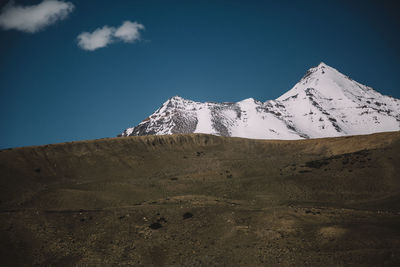 Built structure on snowcapped mountain against blue sky