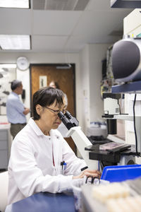 Senior female scientist using microscope in laboratory