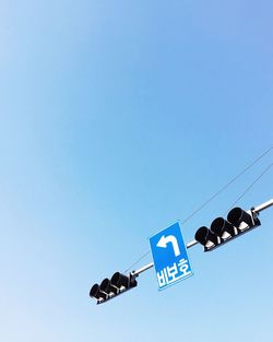 Low angle view of road sign against clear blue sky