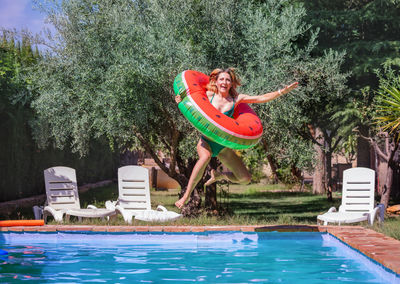 Rear view of woman with arms raised in swimming pool