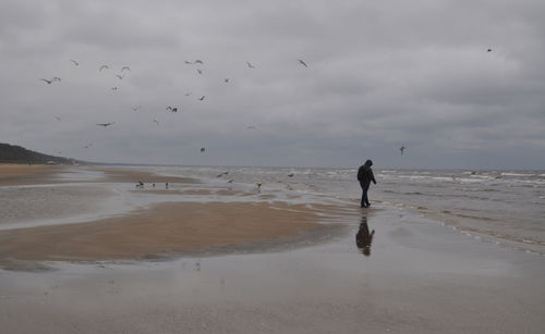 Woman standing on beach against sky