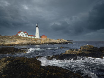 Lighthouse by sea against sky