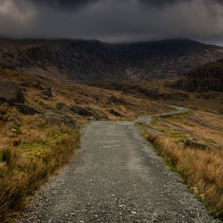 Road leading towards mountain against sky