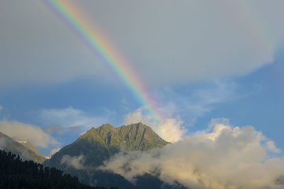 Low angle view of rainbow over mountains against sky