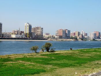 Buildings by river against sky in city