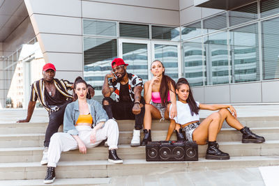 Dancers sitting on steps against building in city