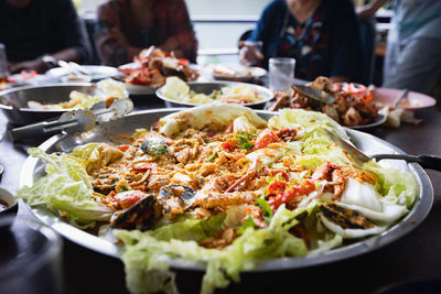 Leftover food and vegetables on the large plate after eating seafood party in the restaurant.