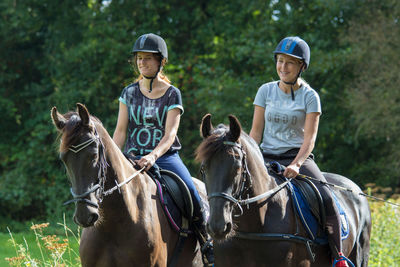 Teenagers riding horse against trees