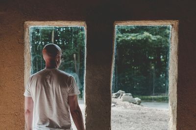 Bald man standing in front of window