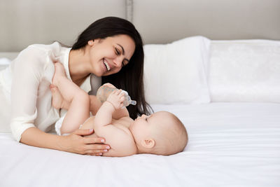 Portrait of mother and daughter on bed at home