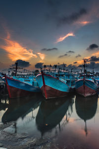 Boats moored at harbor against sky during sunset