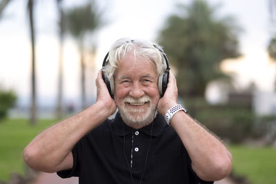 Smiling senior man listening music in park