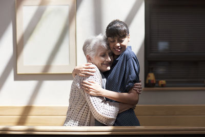 Nurse embracing senior woman in retirement home