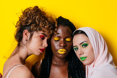 Portrait of young woman against yellow background