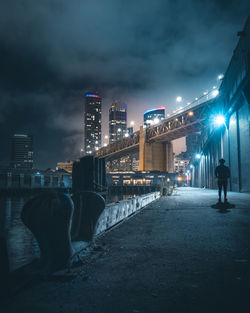 Rear view of man standing at illuminated city against sky